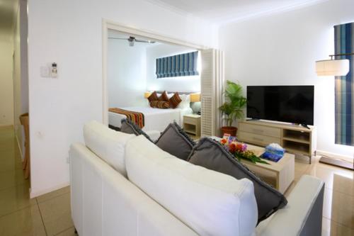 uma sala de estar com um sofá branco e uma televisão em Heritage Park Hotel em Honiara