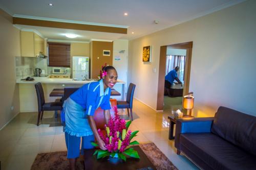 Una donna in piedi in un soggiorno con un vaso di Heritage Park Hotel a Honiara