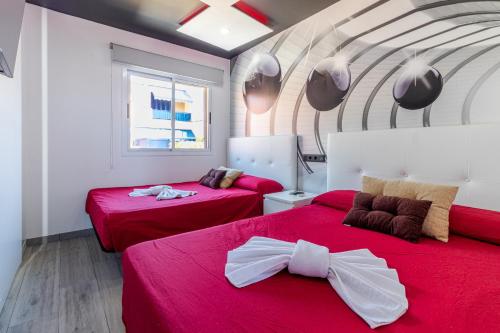 due letti in una stanza con lenzuola rosse e fiocchi di Bahia Meloneras a San Bartolomé