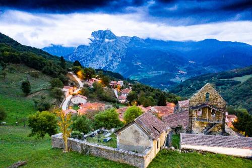 a village on a hill with mountains in the background at Apartamentos Los Picos de Europa in Colio