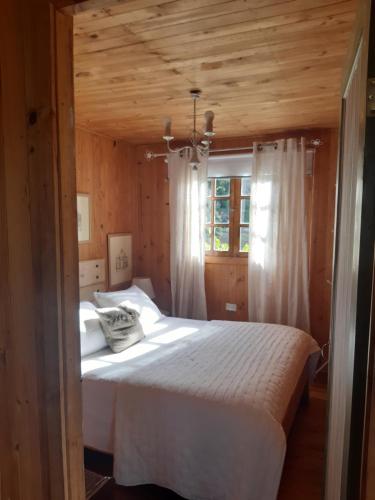 a bedroom with a white bed in a wooden room at Cabañas Puente Negro in Puente Negro