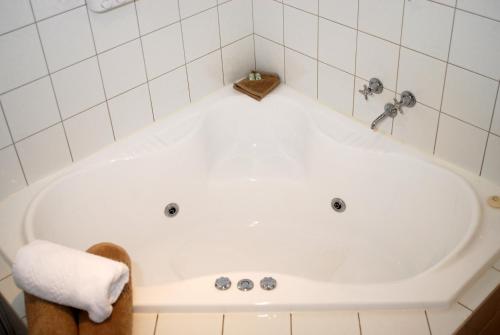 a white bath tub in a white tiled bathroom at Melton Motor Inn and Apartments in Melton