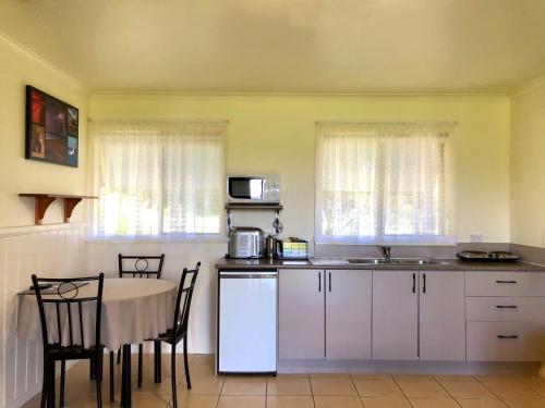 a kitchen with a table and a table and chairs at Promhills Cabins in Yanakie