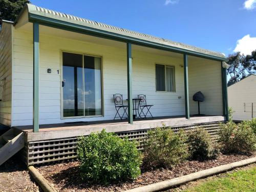 a house with a porch with two chairs at Promhills Cabins in Yanakie