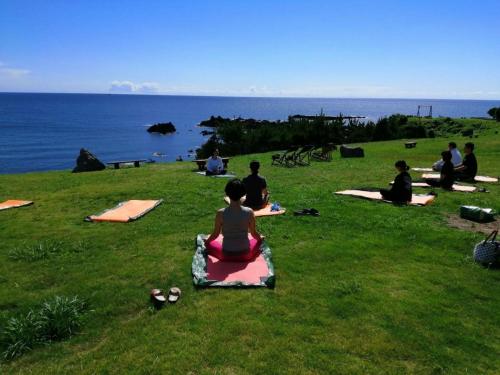 a group of people sitting on the grass in a field at Sado Resort Hotel Azuma in Sado
