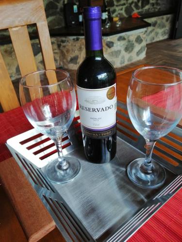 a bottle of wine and two glasses on a table at Mazamitla Pinos del Rio in Mazamitla
