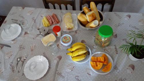 einen Tisch mit Teller und Schalen mit Lebensmitteln in der Unterkunft Hospedaria Casa de Maria in Angra dos Reis