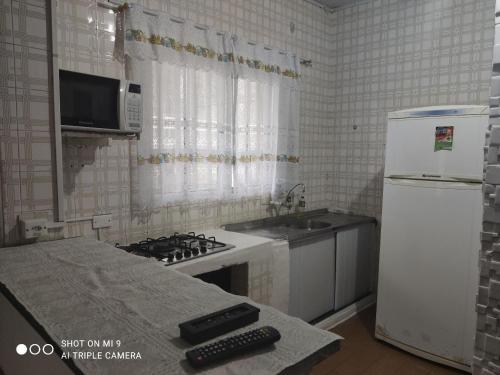 a kitchen with a stove and a white refrigerator at Recanto in Mongaguá