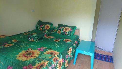 ein Schlafzimmer mit einem Bett mit einer grünen Bettdecke und einem blauen Tisch in der Unterkunft Penginapan Biringta in Berastagi