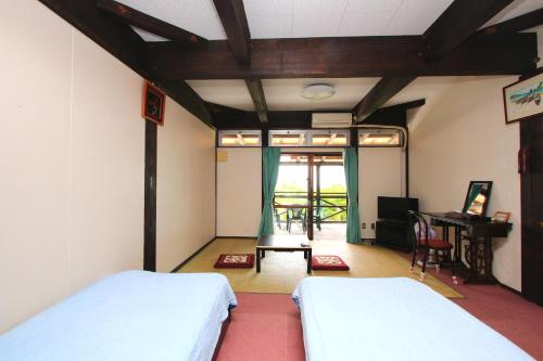 1 dormitorio con 2 camas, mesa y escritorio en Kazenooka en Motobu