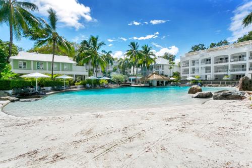 a swimming pool at a resort with palm trees at Palm Cove Beach Club Apartment - Privately Managed in Palm Cove