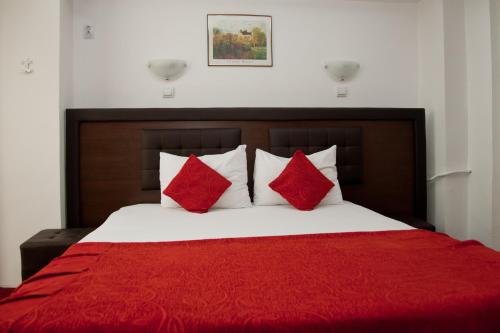 a bedroom with a bed with red sheets and pillows at Hotel Metropol in Piteşti