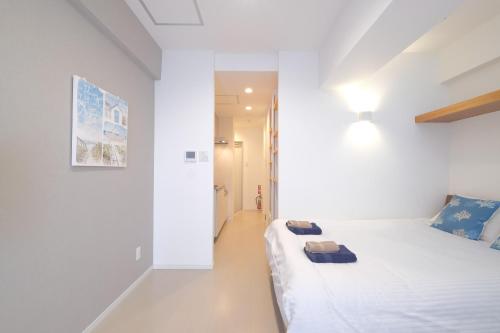 a white bedroom with a bed and a hallway at Good Life Apartment in Naha