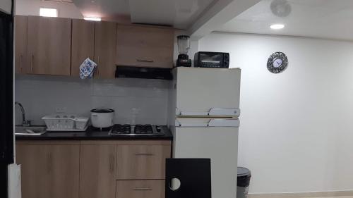 eine Küche mit einem weißen Kühlschrank und Holzschränken in der Unterkunft Apartamento Ynj Bogot in Bogotá
