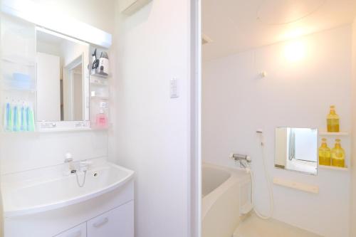 a white bathroom with a sink and a bath tub at Good Life Apartment in Naha