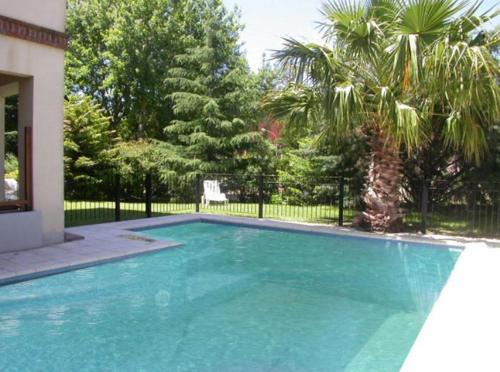 una piscina en un patio con árboles y una valla en Las Araucarias, en Pinamar