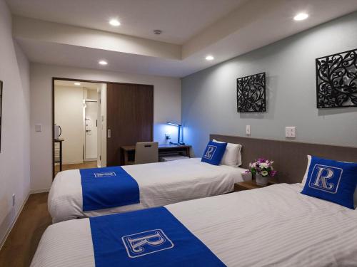a hotel room with two beds with blue and white at Living Inn Asahibashiekimae Premier in Naha