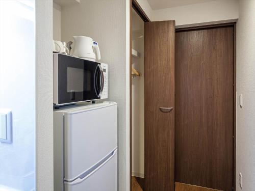 a microwave on top of a refrigerator in a room at Living Inn Asahibashiekimae Premier in Naha