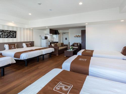 a hotel room with three beds and a living room at Living Inn Asahibashiekimae Premier in Naha