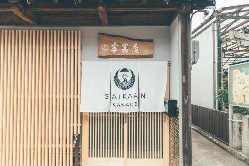 een bord aan de zijkant van een gebouw bij ゲストハウス 宰嘉庵 かなで GuestHouse Saikaan KANADE in Maizuru