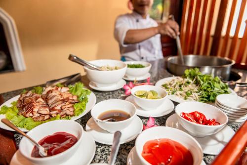 een tafel met borden en kommen eten bij White Sand Resort Mui Ne in Mũi Né
