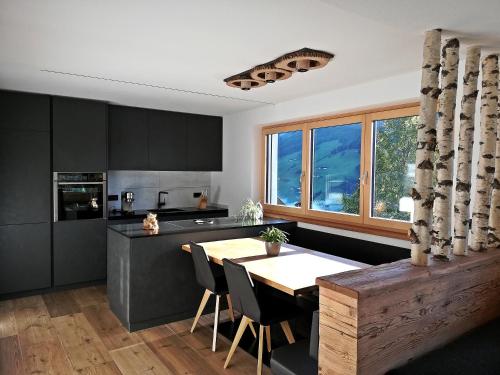 kuchnia z czarnymi szafkami i drewnianym stołem w obiekcie Nature luxury Chalet INSToul w mieście Lutago