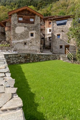 a stone house with a grass yard in front of it at Agriturismo Cà Gianin in Vervio