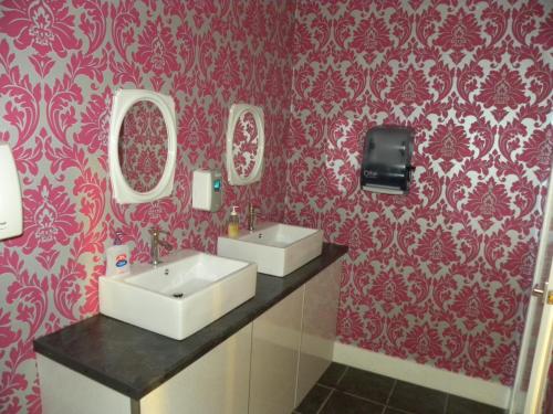a bathroom with two sinks and red wallpaper at The Davron Hotel in Fraserburgh