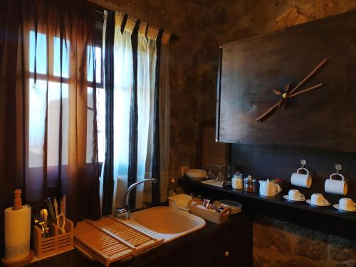 een badkamer met een wastafel en een klok aan de muur bij Ξενώνας Λίκνο in Synikia Mesi Trikalon