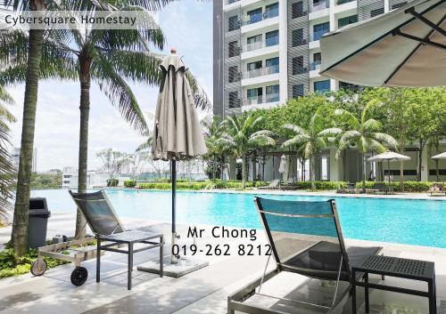 two chairs and an umbrella next to a swimming pool at Cybersqaure Studio Suites with Netfilx @10 min walking distance to McD in Cyberjaya