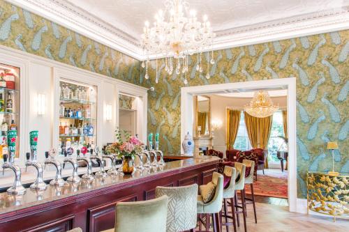a restaurant with a bar with chairs and a chandelier at Cork's Vienna Woods Hotel & Villas in Cork