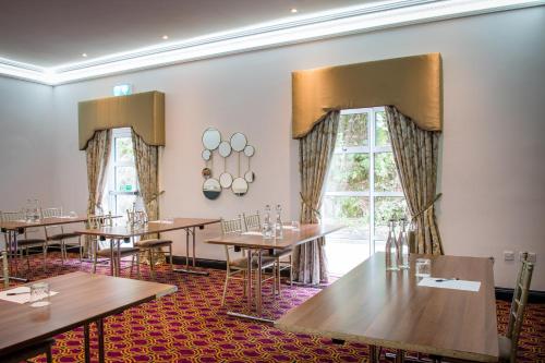 a dining room with tables and chairs and a window at Cork's Vienna Woods Hotel & Villas in Cork