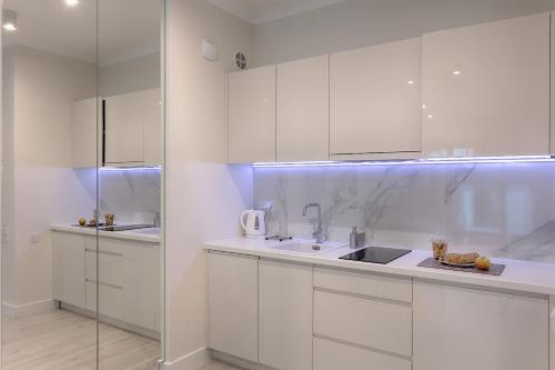 ワルシャワにあるMennica Residence Iの白いキッチン(白いキャビネット、シンク付)