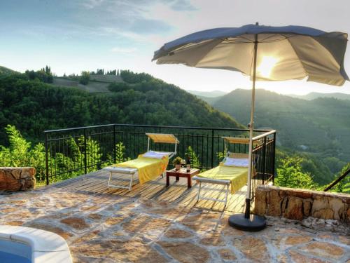 un patio con 2 sillas y una sombrilla en Bright Holiday Home in Modigliana with Swimming Pool en Modigliana