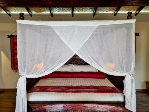 a bed with a canopy with a red and white blanket at The Zarafa in Hazyview