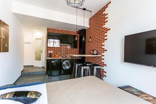 een woonkamer met een bakstenen muur en een keuken bij Relaxhome - Hypercentre - Clim - Netflix in Cannes