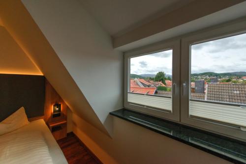 a bedroom with a bed and two windows with a view at Heidequartier Harz in Wernigerode