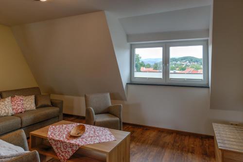 a living room with a couch and a table and a window at Heidequartier Harz in Wernigerode