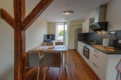 a kitchen with white cabinets and a wooden table at Heidequartier Harz in Wernigerode