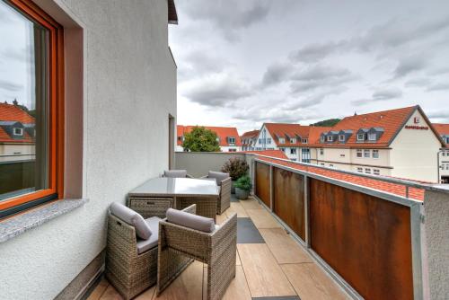 a balcony with wicker chairs and a table on a building at Heidequartier Harz in Wernigerode