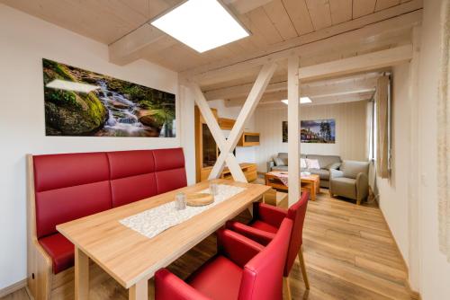 a dining room with a table and red chairs at Heidequartier Harz in Wernigerode
