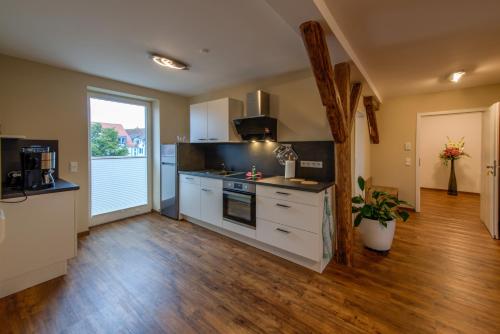 a large kitchen with white cabinets and a wooden floor at Heidequartier Harz in Wernigerode