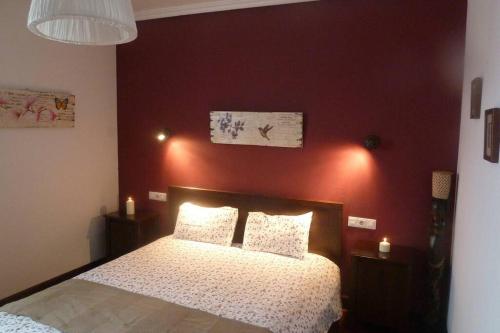 a bedroom with a bed with a red wall at Casa rural Mertxenea Landetxea in Elcano