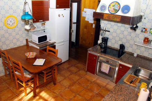 a kitchen with a wooden table and a small table and a kitchen with a refrigerator at Casa rural Mertxenea Landetxea in Elcano