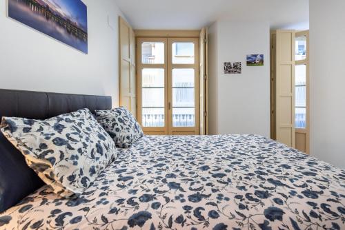 a bedroom with a bed with a blue and white comforter at Apartamento Soho Málaga in Málaga