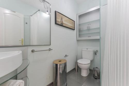 a bathroom with a toilet and a sink and a mirror at Merlín 1-1 in Playa de San Juan