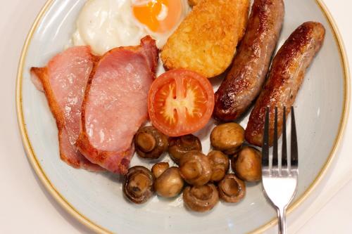 a plate of breakfast food with eggs bacon sausage and mushrooms at Holiday Inn Ashford - North A20 by IHG in Ashford
