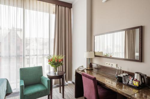 a hotel room with a desk and a mirror at Europeum Hotel in Wrocław