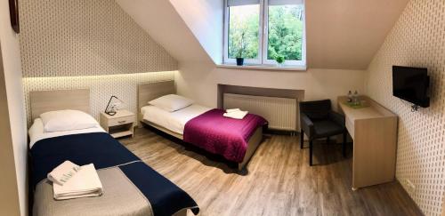 Habitación con 2 camas, escritorio y TV. en Restauracja Park Szwajcaria en Gliwice