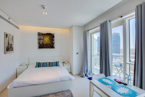 een witte slaapkamer met een bed en een raam bij Stylish Studio in West Avenue Dubai Marina in Dubai